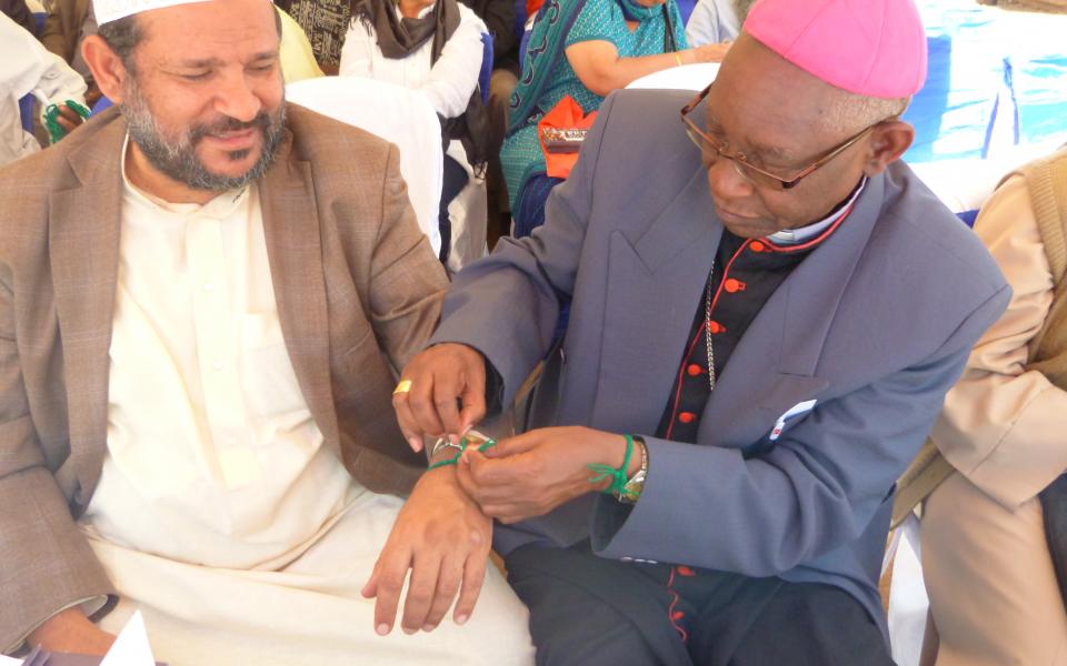His grace Peter Kairu and Sheikh Abdul tie each other peace ribbons.jpg 