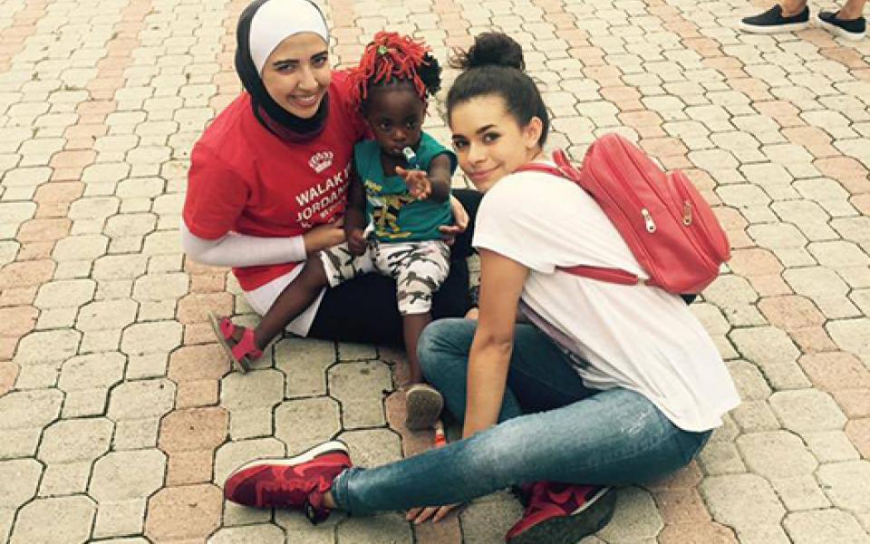 two young girls caring for young refugee child 