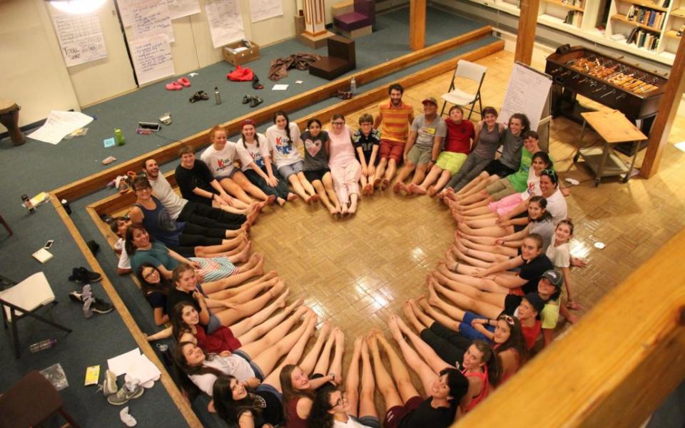 Kids sit in a circle in the shape of a heart