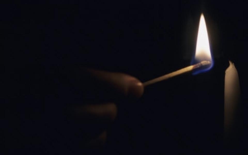 a man is lighting a candle with black background on sight 