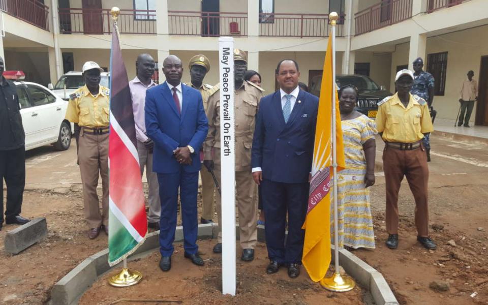 People standing in front of two poles with flags on them